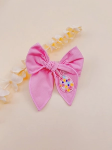 Close-up of pink fabric bow hair clip featuring detailed rabbit and egg embroidery