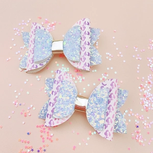 Détail de barrettes papillon en léopard rose et paillettes bleues avec centre doré