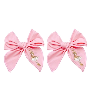 Close-up of pink fabric bow hair clips with detailed gold ballet dancer embroidery