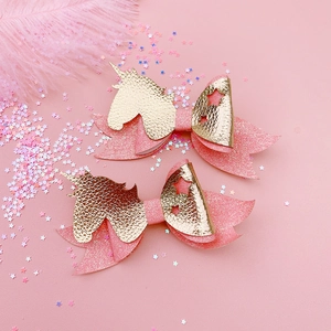 Detail of pink glitter unicorn hair clips with leather stars and feather background