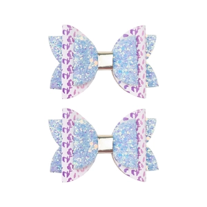 Détail de pinces à cheveux papillon en tissu pailleté bleu et motif léopard violet