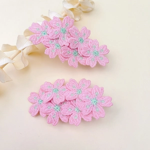 Close-up of pink embroidered flower hair clips with intricate floral petal textures