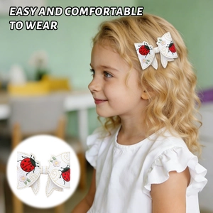 Close-up of child bow hair clip with ladybug embroidery and yellow decorative stitching