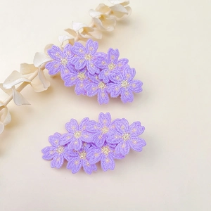Detailed macro view of purple embroidered flower hair clips with golden centers