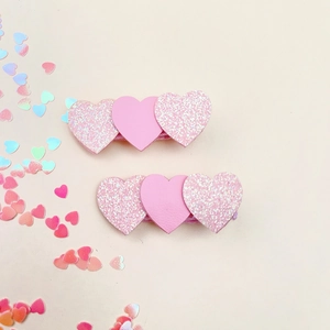 Pinces à cheveux en forme de cœur rose avec paillettes et pompons sur fond crème