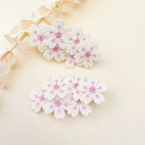 Detailed close-up of white embroidered cherry blossom hair clips with pink floral stamens