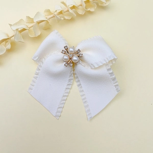Dettaglio del fermaglio per capelli a fiocco bianco con perle eleganti e strass lucenti