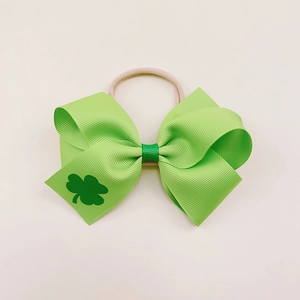 Detail of green grosgrain ribbon bow with shamrock print on soft nylon baby headband