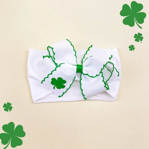 Detail of baby headband with white ribbed bow and green clover print for St. Patrick's Day