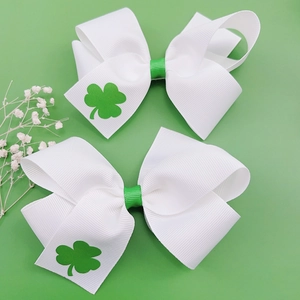 Détail de barrettes de la Saint-Patrick avec motifs trèfles sur nœuds de ruban blanc