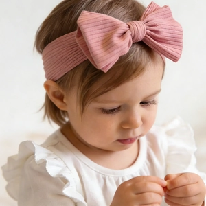 Close-up of soft pink ribbed knit baby headband featuring a large decorative bow tie