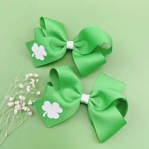 Détail de barrettes à cheveux en ruban vert avec motifs de trèfles blancs pour la St Patrick