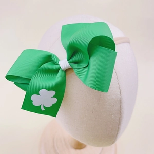 Close-up of St. Patrick's Day green bow headband with white shamrock and nylon strap
