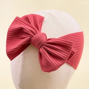 Detail of rose red ribbed knit headband with large 3D bow on mannequin head