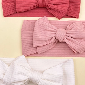 Close-up of ribbed texture and oversized bows on three colorful elastic baby headbands