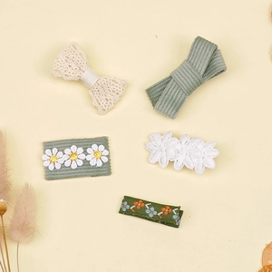Détail de 5 barrettes à broderie florale en tissu pour filles sur fond crème doux