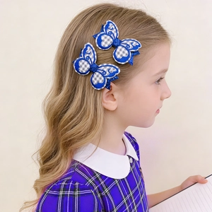Détail de la pince à cheveux papillon pailletée bleue brodée sur modèle enfant