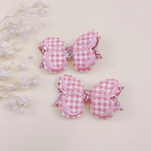 Vue détaillée de deux barrettes papillon brodées avec paillettes roses et tissu à carreaux