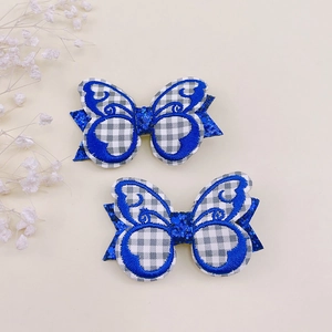 Détail de barrettes papillon brodées avec paillettes et motif à carreaux