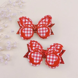 Détail de barrettes papillon à carreaux rouges et blancs avec paillettes et broderie décorative