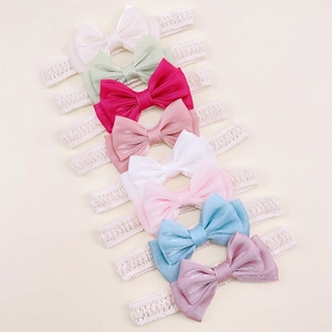Detail showing eight-piece set of baby bow headbands in various colors with lace ribbons