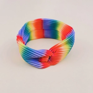 Close-up of rainbow gradient sports headband with twisted knot design and ribbed texture
