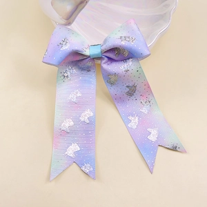 Close-up of rainbow gradient bow hair clip featuring silver glitter unicorn patterns