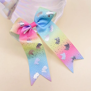 Macro view of rainbow gradient ribbon bow hairclip featuring glittery silver unicorn print