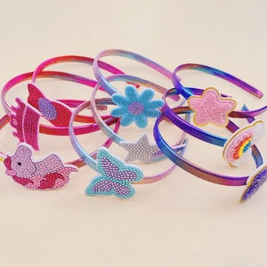 Close-up of glittery fabric headbands for girls with rhinestone crowns and colorful patterns