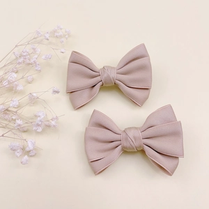 Détail de deux barrettes à cheveux rose clair avec texture tissu et design élégant chic