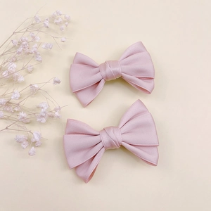Détail de pinces à cheveux en satin rose clair faites main avec tissu multicouche et clip