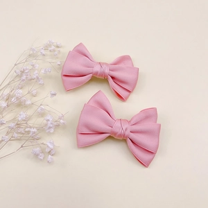 Détail de deux barrettes en satin rose avec des nœuds en ruban faits main pour filles