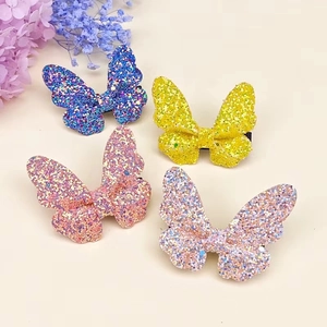 Detail of four glittery butterfly hair clips in blue, yellow, pink, and rainbow colors