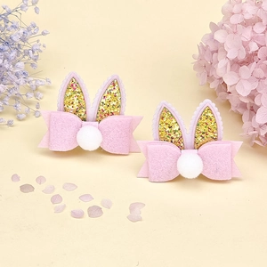 Détail de pinces à cheveux oreilles de lapin roses avec paillettes et pompons en peluche