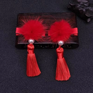Macro shot of traditional Chinese hair clips with red pom-poms, pearls and long tassels
