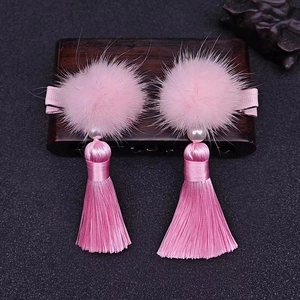 Detail of pink faux fur pom-pom hair clips with long silk tassels and pearl accents