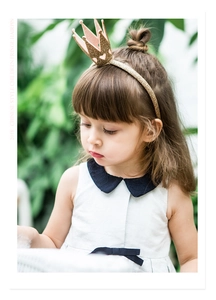 Detail view of a glittery golden crown headband with heart cutouts on a little girl