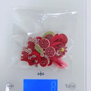 Close-up of red rhinestone cherry and watermelon elastic hair ties on a digital scale