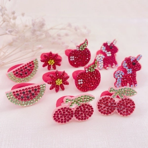 Detailed view of handmade red rhinestone hair ties featuring cherry and apple shapes