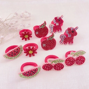 Detail of red rhinestone fruit hair ties featuring cherry watermelon and apple shapes
