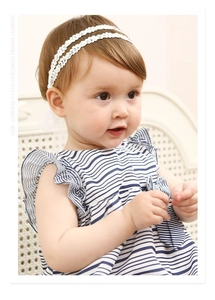 Détail du bandeau en dentelle pour bébé avec strass et robe à rayures bleues
