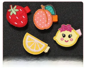 Gros plan sur les barrettes à broderie de fruits avec détails de couture fins pour bébés