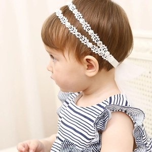 Gros plan du bandeau en dentelle pour bébé avec perles blanches et strass brillants