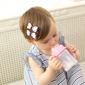 Pink and blue polka dot hair bows for girls, 2-piece set shown on toddler model