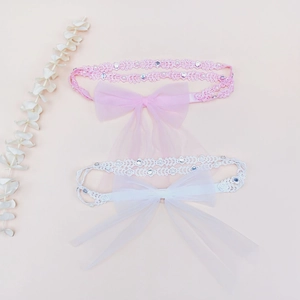 Détail de bandeaux pour bébé en dentelle rose et blanche avec nœuds et strass brillants