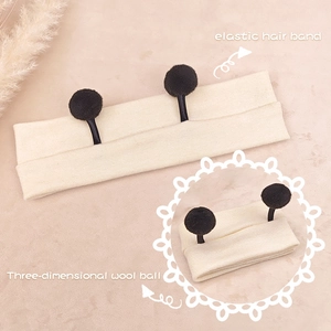 Detail showing cream knitted elastic hair band with 3D black wool balls for babies