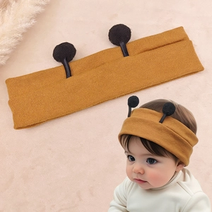 Detail of ginger yellow knitted baby headband with cute bee antennae and soft texture