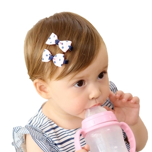 Toddler girl wearing pink bow hair clips with navy polka dots in a natural lifestyle setting