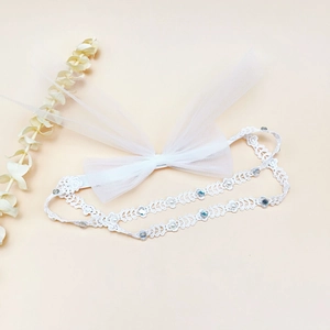 Détail d'un bandeau pour bébé en dentelle blanche avec nœud en maille et perles