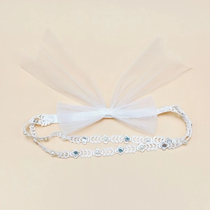 Détail d'un bandeau bébé en dentelle blanche avec gros nœud en résille et perles